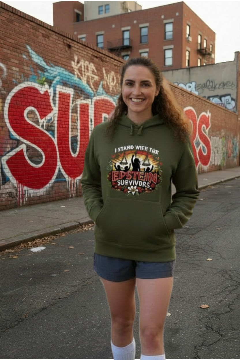 Smiling woman in green Blooms of Resilience Epstein Survivor hoodie, healing and hope, standing beside graffiti.