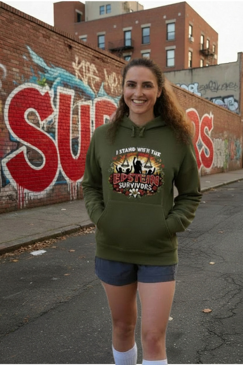 Smiling woman in green Blooms of Resilience Epstein Survivor hoodie, healing and hope, standing beside graffiti.
