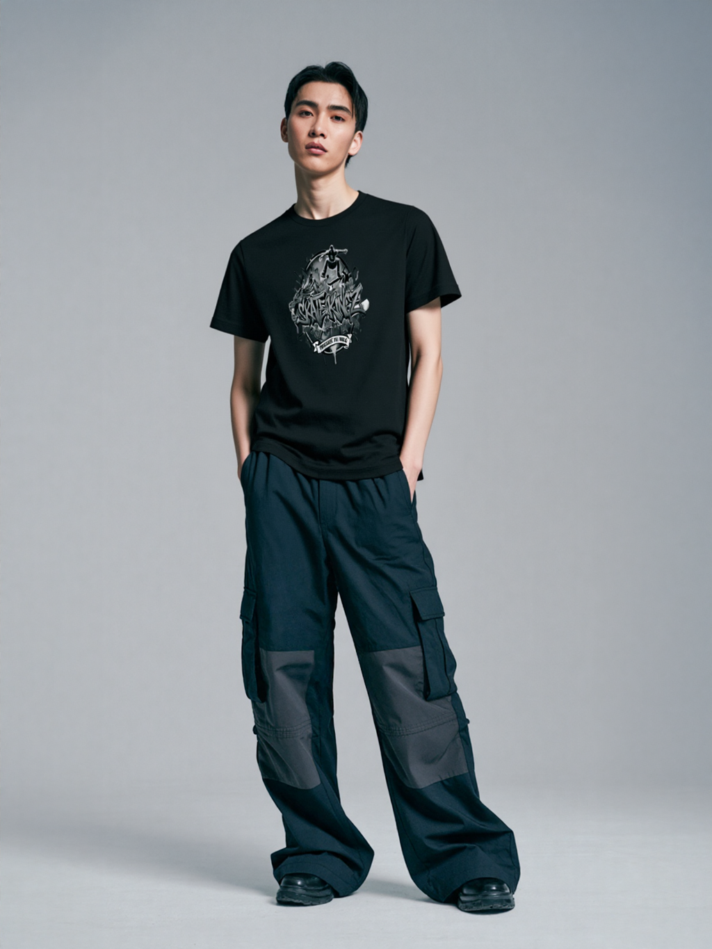 Skatekingz black skateboard t-shirt for enthusiasts worn by model with graphic logo, paired with dark cargo pants.