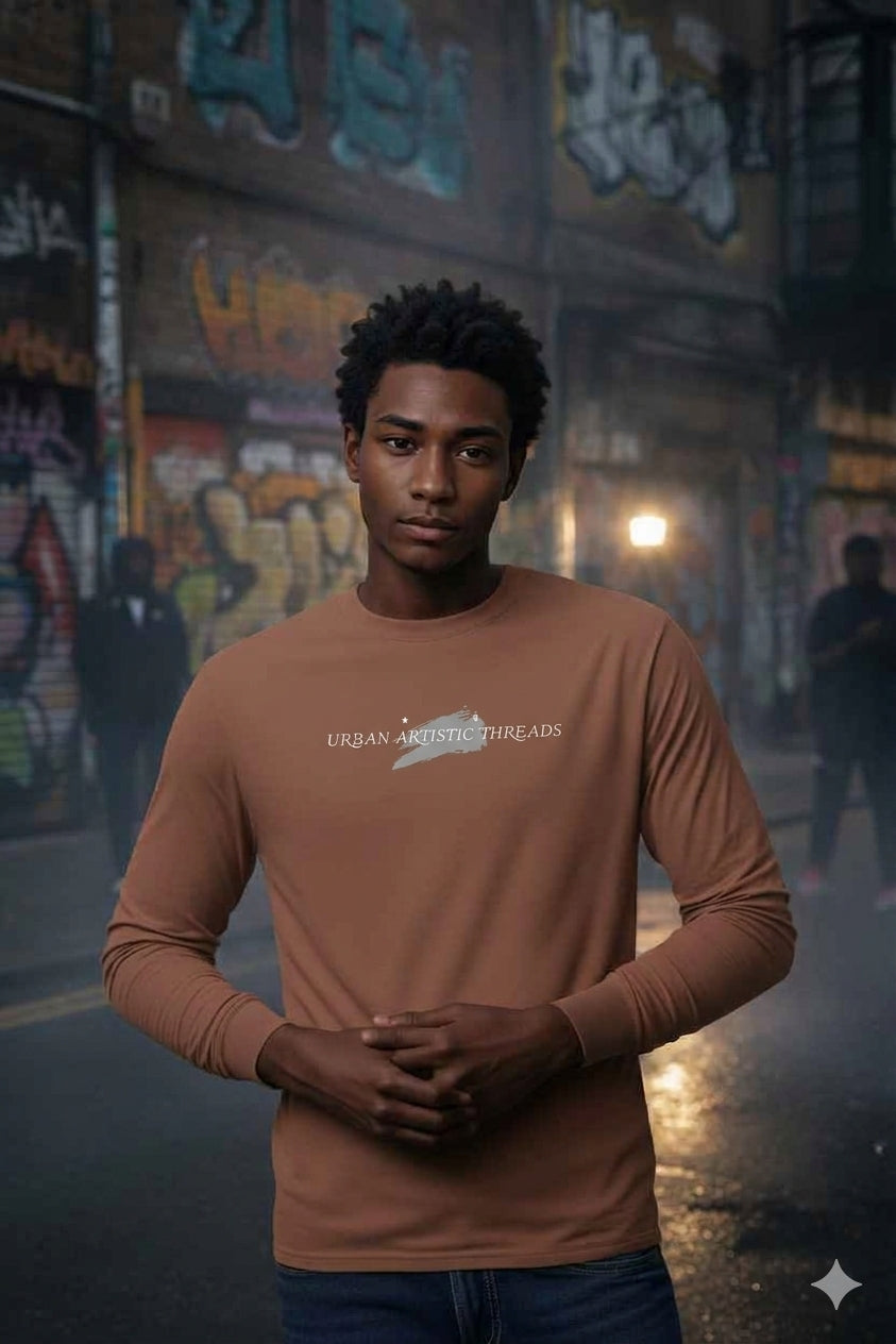 Urban Artistic Threads Signature long sleeve tee in brown with brushstroke logo, styled for street culture against a graffiti background.